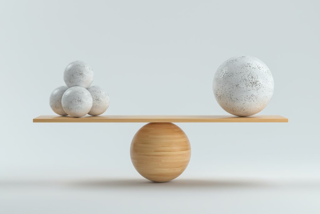 wooden scale balancing one big ball and four small ones