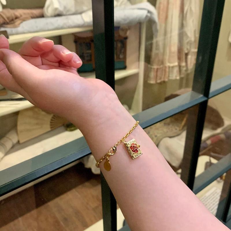 the 18ct gold plated bracelet is shown here on a model. The beautiful hand painted enamel rose shines in the warm light. 