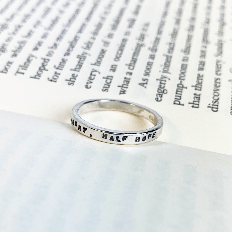 The Persuasion, half agony half hope ring displayed on a book page. A lovely Jane Austen gift for any regency lovers