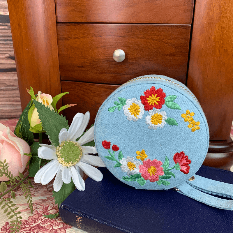 Here the jewellery box is shown with the embroidered flowers on display. The floral arrangments decorate the top of the box in a variety of colours that pair well with the blue faux saude