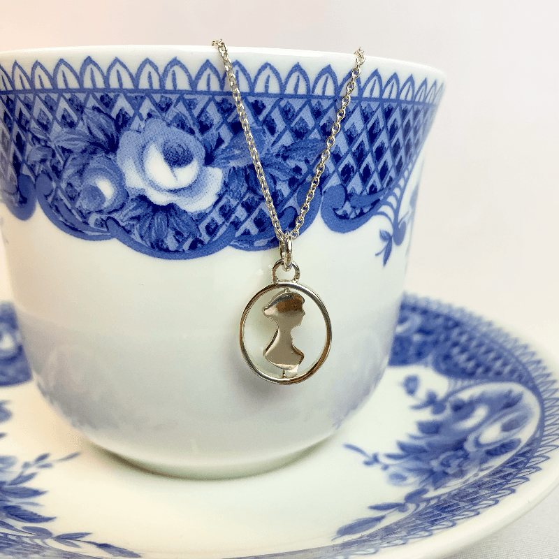 here you can see the necklace face on with the silhouette spun to face the right hand side. the necklace is hung from a vintage teacup suitable for the regency era.